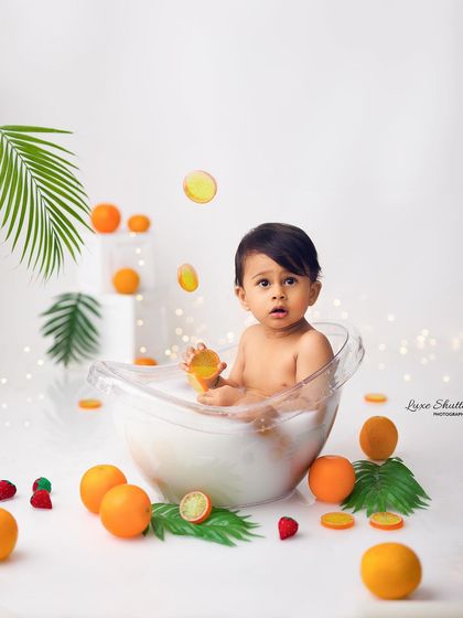 A fun and creative fruit bath milestone session. This baby is looking up with curiosity as fruit slices appear to fall around him.