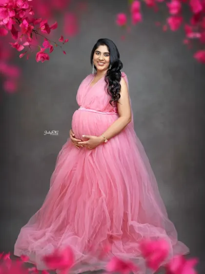 A beautiful solo portrait of this mama in a flowing pink tulle gown. The simple grey backdrop and floral details make her and the baby bump the true stars of the photo.