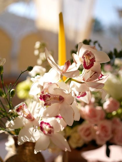 A close-up of a white orchid with a distinctive pink center, part of a larger floral arrangement.