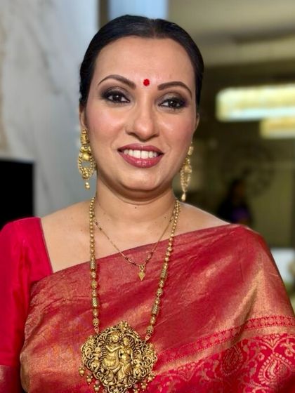 A radiant, smiling portrait. The makeup enhances her warm smile, with a focus on glowing skin and a classic lip color that brightens her entire face.