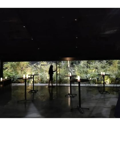 The interior of the Durall Pavilion, where a horizontal window frames a lush garden. The all black space becomes a quiet backdrop, allowing the view and the people within it to become the focus.