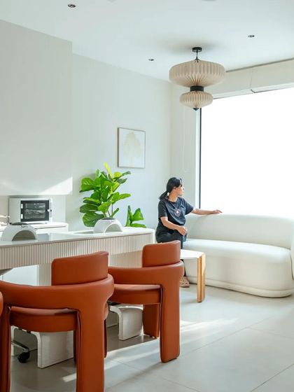 A comfortable waiting area with a curved white sofa and large window allows clients to relax in a light-filled space.