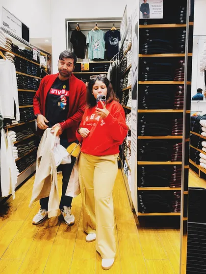A mirror selfie with my husband, both in red, during a shopping trip at Uniqlo.