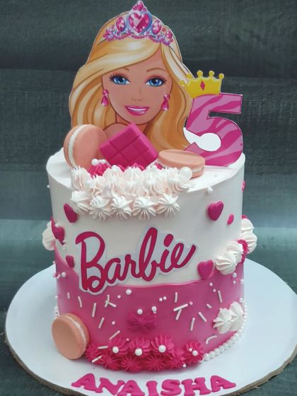 A fun and stylish Barbie cake with a choco-chip flavor. This tall cake is decorated with pink macarons and lots of hearts for a 5th birthday.