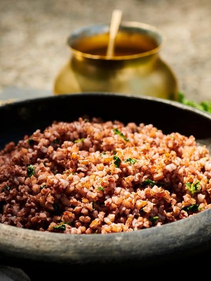A bowl of nourishing red rice, a staple of the Ayurvedic diet, served in a traditional stone bowl. This wholesome grain is easy to digest and provides sustained energy.