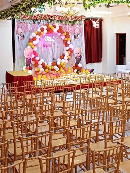 The hall set up for a 'Boss Baby' themed baby shower, showing the seating capacity and the stage decoration.