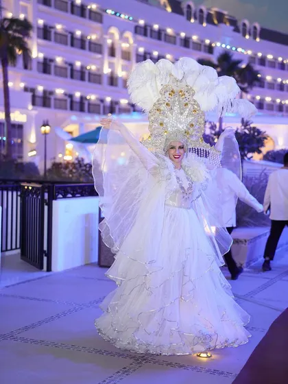 A performer in an angelic, illuminated white costume with large feathered wings, greeting guests and adding a touch of ethereal magic to the evening.