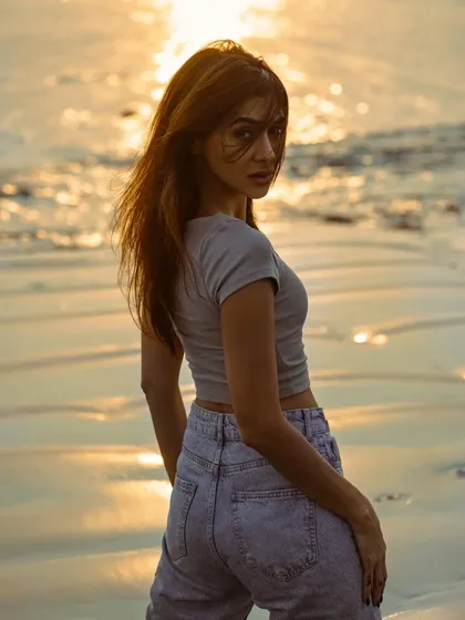 A classic over-the-shoulder pose during the golden hour. The warm light on the water and the model's hair creates a beautiful, glowing effect.