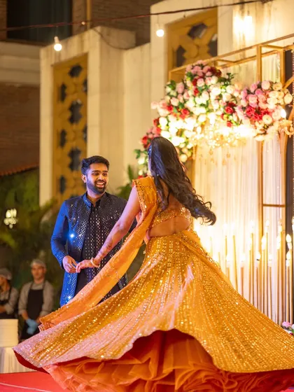 A bride's joyful twirl on the Sangeet stage. The golden lehenga shines under the stage lights, a moment of pure elegance and happiness that I help create through careful planning of lighting and stage design.