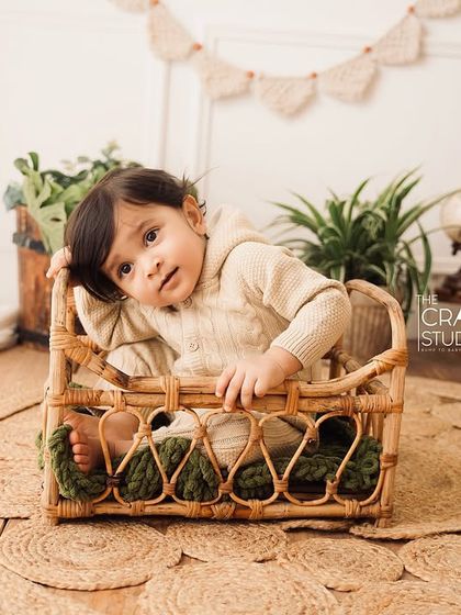 A curious little one peeks out from a wicker basket during his sitter session. The neutral tones and natural textures create a timeless, earthy feel.