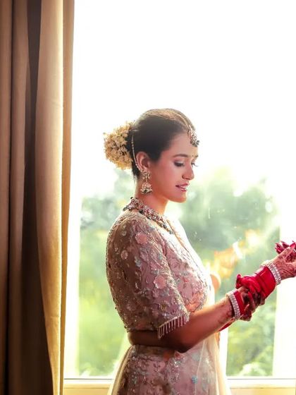 A bride gets ready by a window, the natural light creating a beautiful silhouette.