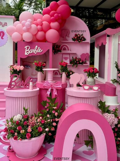 A detailed shot of the Barbie dessert station, featuring a 'doll in a box' prop, themed stands, and floral arrangements.