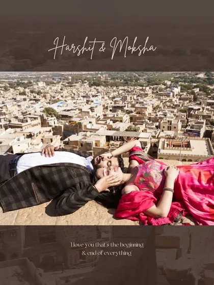 A unique aerial-view perspective of a couple relaxing on the ramparts of a Jaisalmer fort, with the sprawling golden city below them, blending history with a modern love story.