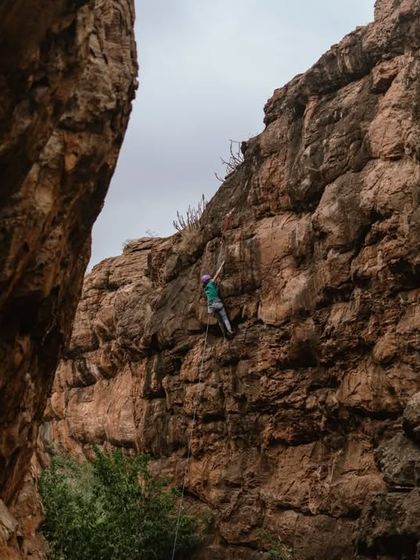 A climber scales a massive cliff face in Badami. The scale of these sport climbing routes is breathtaking and offers a completely different challenge from bouldering.