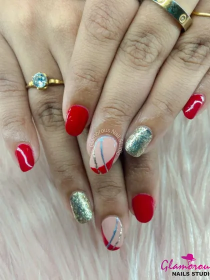 This design pairs classic red nails with full-coverage gold glitter accent nails and abstract line art for a modern, edgy look.