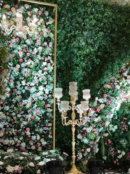 A breathtaking reception stage where a wall of lush greenery is densely packed with a variety of pastel flowers. This design creates the feel of an enchanted garden, complete with elegant candelabras and chandeliers.