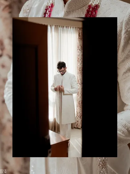A creative shot of the groom getting ready, viewed through a doorway for an interesting perspective.