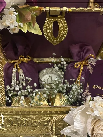 A closer look inside the Rajwada Chest, revealing velvet potlis, a delicate silver candle, and other curated items nestled amongst baby's breath. Each element is carefully placed to create a breathtaking unboxing experience for the recipient.