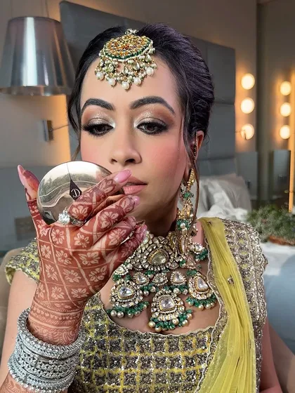A moment of reflection. The makeup looks flawless from every angle, and the highlighter gives her skin a beautiful sheen.