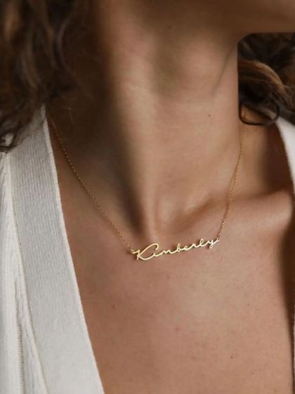 The 'Kimberly' script necklace shown on the model, providing a clear example of how this piece sits and complements the neckline.