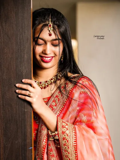 A close-up of the bride's joyful, shy smile as she leans against a wooden door, capturing an intimate and candid moment.