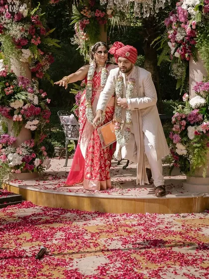 Sandhita and Siddhant after their pheras. The ground is covered in petals, and a dropped mic hints at a funny story. These are the real, unscripted details that make each wedding unique.