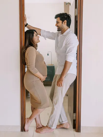 A playful and loving pose in a doorway. Using architectural elements like this at home can help frame the couple and add a dynamic, fun element to the photoshoot.