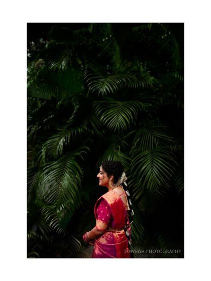 A beautiful bridal portrait against a backdrop of lush palm leaves. The contrast between her pink saree and the deep green is stunning.