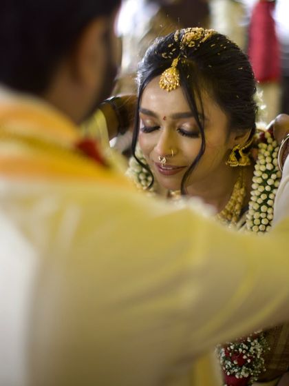 An emotional, heartfelt moment as the groom ties the mangalsutra. The bride's closed eyes and serene expression convey the depth and solemnity of this pivotal part of the wedding ceremony.