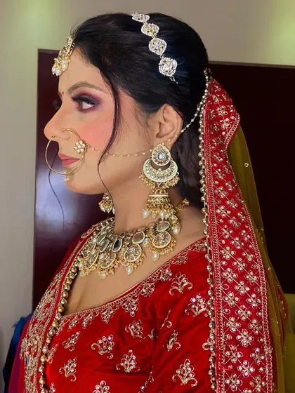 This profile shot highlights the intricate details of the bridal hairstyle and jewelry placement. Every element, from the nose ring to the hair accessories, is carefully chosen and placed.
