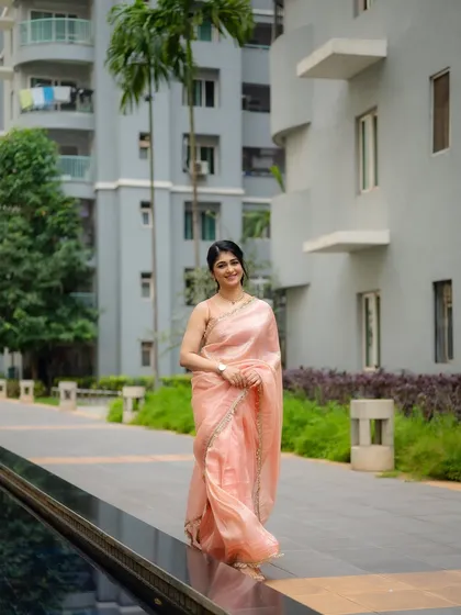A candid shot of actress Aditi Prabhudeva walking in a beautiful peach saree. The urban garden setting provides a modern context for this elegant traditional wear.