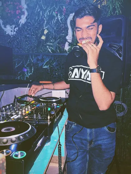 Even a DJ needs a snack break. Caught in the act of grabbing a slice of pizza mid-set without missing a beat.