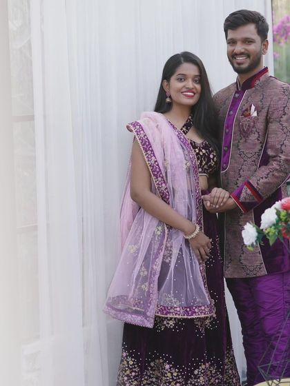 This full-length shot shows the beautiful coordination between the embroidered purple lehenga and the patterned sherwani, a perfect rental set for couples.