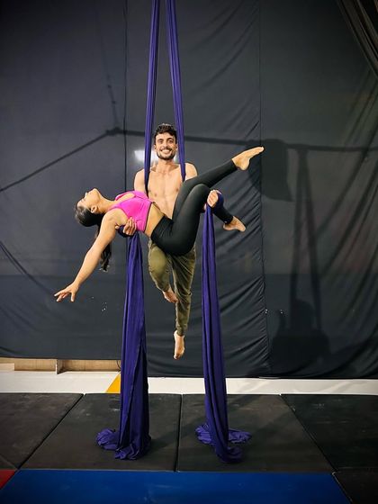 Duet work on the aerial silks involves trust and synchronized strength. Here, two performers create a beautiful, supportive pose together.