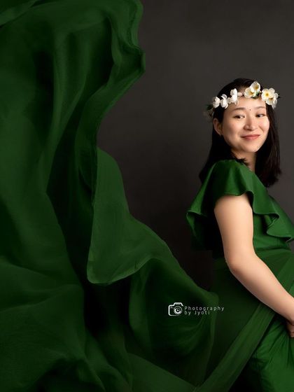A beautiful portrait using a flowing green fabric to add movement and drama against a simple dark background.