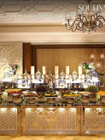 An ornate and brightly lit dessert buffet, featuring traditional Indian sweets and dry fruits presented in intricate silverware. This showcases our expertise in creating lavish displays for wedding celebrations.