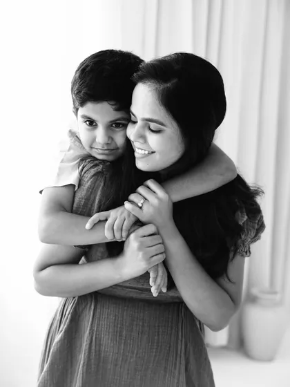 A black and white portrait filled with peace and affection. The son's gentle hug and the mother's serene smile create a timeless and emotional image.