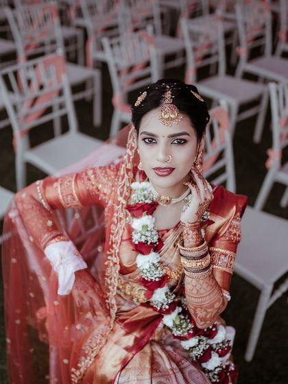 A stunning high angle portrait of the bride seated amongst the guest chairs before the ceremony. Her direct gaze and beautiful makeup make this a powerful image.