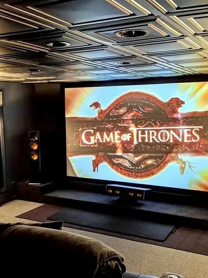 An example of a truly immersive themed environment, this home cinema features a massive projection screen perfect for epic series like Game of Thrones. The design incorporates a decorative coffered ceiling and strategically placed tower speakers to create a powerful, enveloping soundstage that transports you directly into the story.