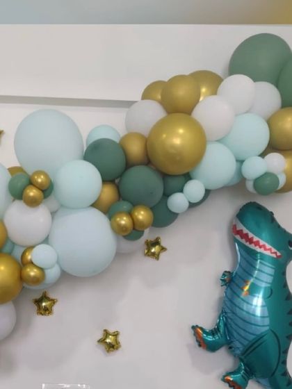 A simple yet effective dinosaur-themed organic balloon garland. The mix of sage green, white, and gold balloons, accented with gold star foils and a large dinosaur balloon, creates a stylish and modern take on the theme.