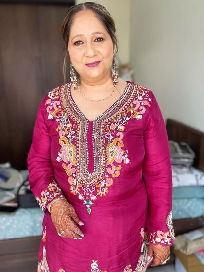 A mother's glow on her son's wedding day. This look features a soft plum lip and defined eyes, complementing her richly embroidered magenta suit.