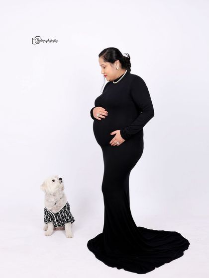 A classic studio portrait of a mother-to-be with her beloved pet, who is looking up at her with adoration.