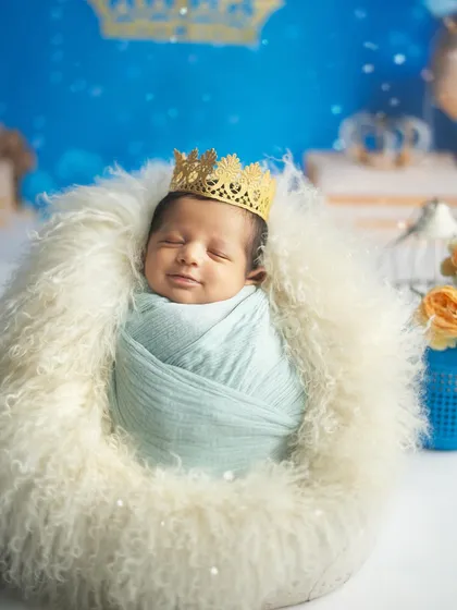 A sleepy little prince, dreaming sweet dreams on his fluffy white throne. The golden crown adds a perfect royal touch.