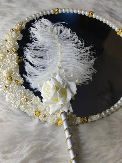 A detailed shot of the white elegance mirror and pen set. The ostrich feather on the pen adds a touch of luxury and softness.