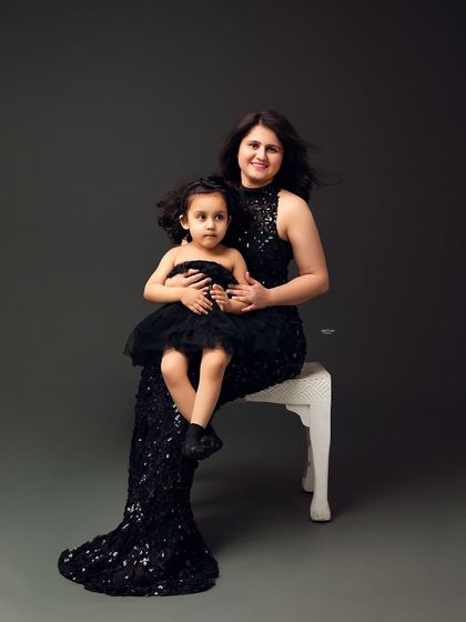 An elegant portrait of a mother and daughter in matching black formalwear.