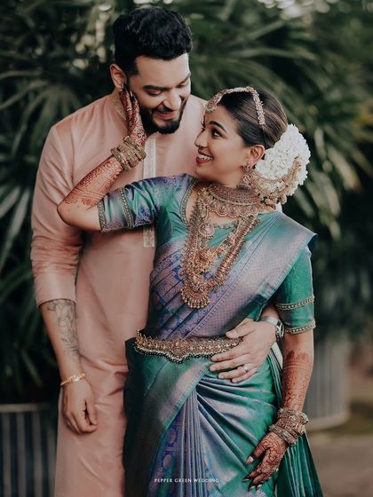 A beautiful portrait of the couple, the bride playfully touching the groom's face, her green saree a stunning contrast to his pink kurta.