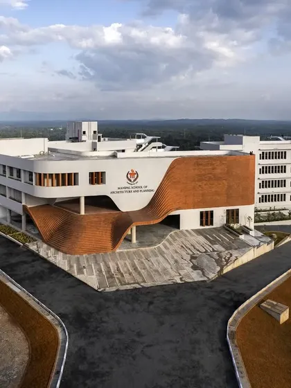 The main entrance of MSAP Manipal, where the undulating brick form creates a powerful visual statement. This element was inspired by traditional temple arches but reinterpreted in a modern architectural language.