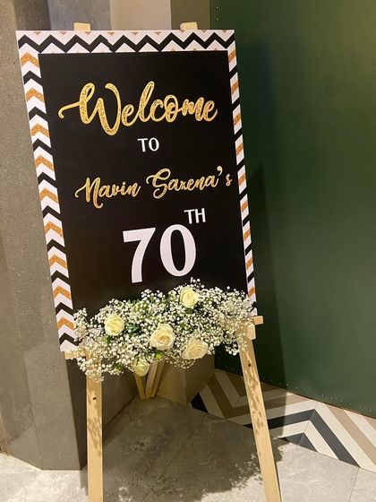 A personalized welcome easel for a 70th birthday dinner. The simple addition of a fresh baby's breath and rose garland adds a touch of elegance to the entrance.