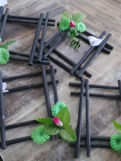 A close-up of photo frames crafted from dark-colored paper rolls and adorned with artificial flowers, showcasing another creative take on our recycled art projects.