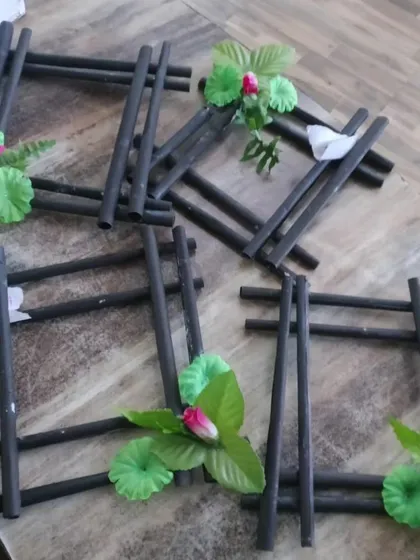 A close-up of photo frames crafted from dark-colored paper rolls and adorned with artificial flowers, showcasing another creative take on our recycled art projects.